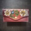 Madison wallet exterior, with 2 cream and white flowers and one blue and cream smaller flower on a brown background