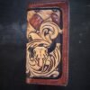 Boulder wallet exterior, brown and tan basketweave background and black boarder. Western scroll and cow skull in lower right corner.