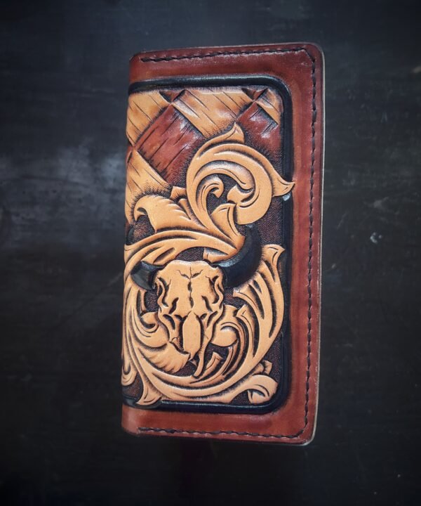 Boulder wallet exterior, brown and tan basketweave background and black boarder. Western scroll and cow skull in lower right corner.