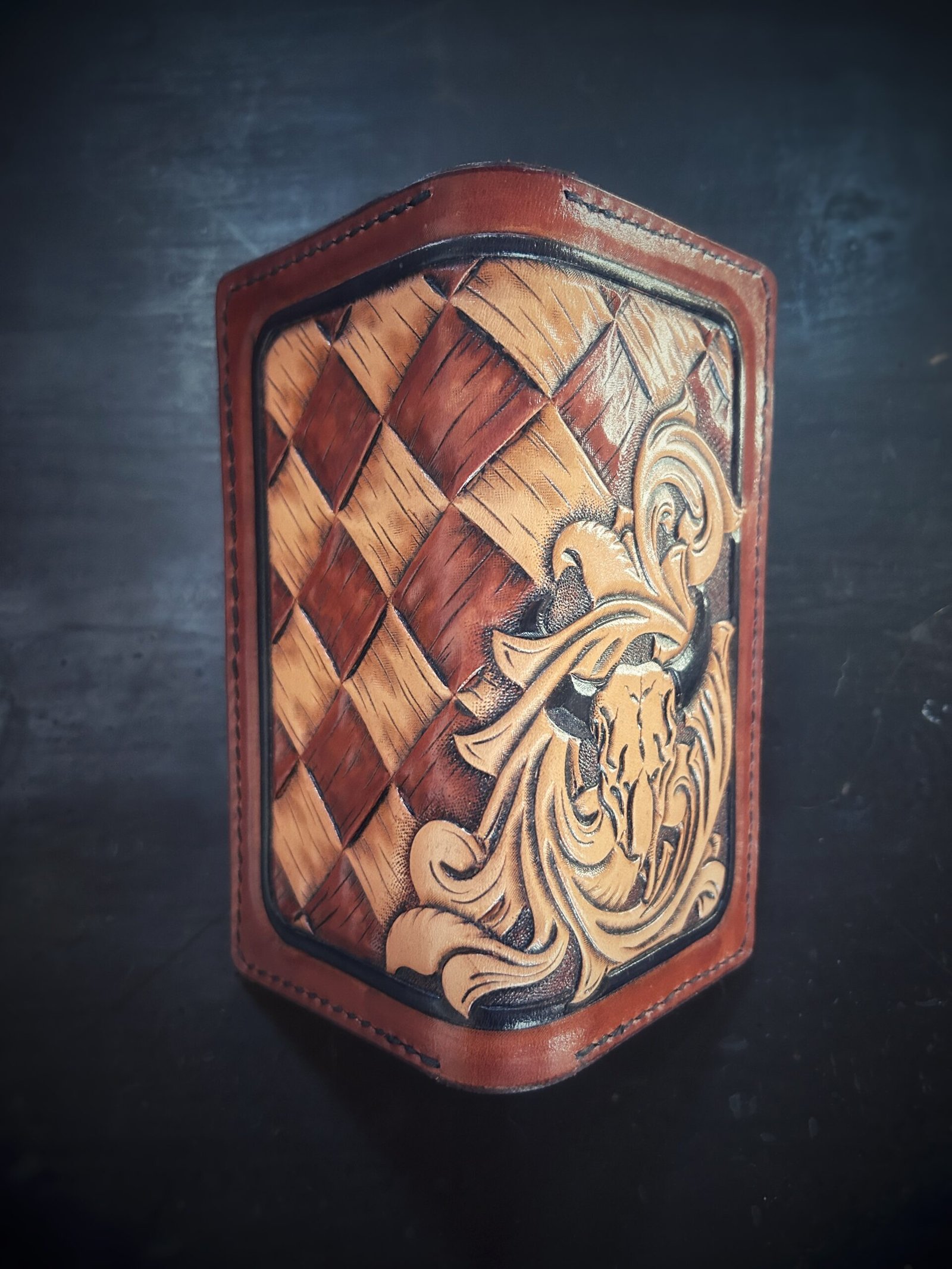 Boulder wallet exterior, brown and tan basketweave background and black boarder. Western scroll and cow skull in lower right corner.