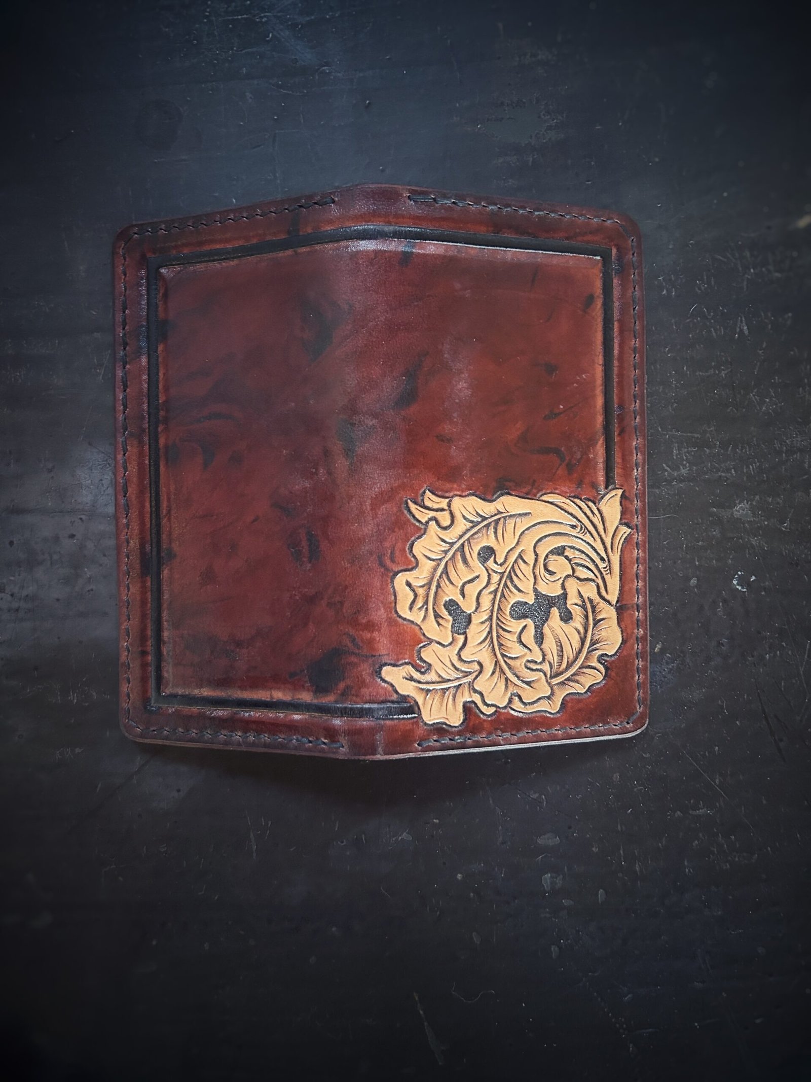 Boulder wallet exterior, brown and black marbled background with black boarder and oak leaves in lower right corner